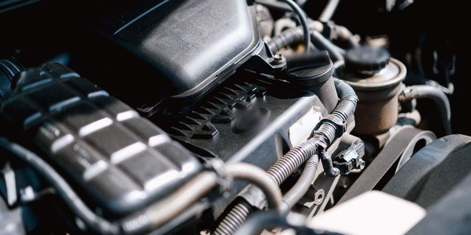 Detalhe do cofre do motor com a tampa de abastecimento de óleo, mangueiras e o reservatório de fluido
